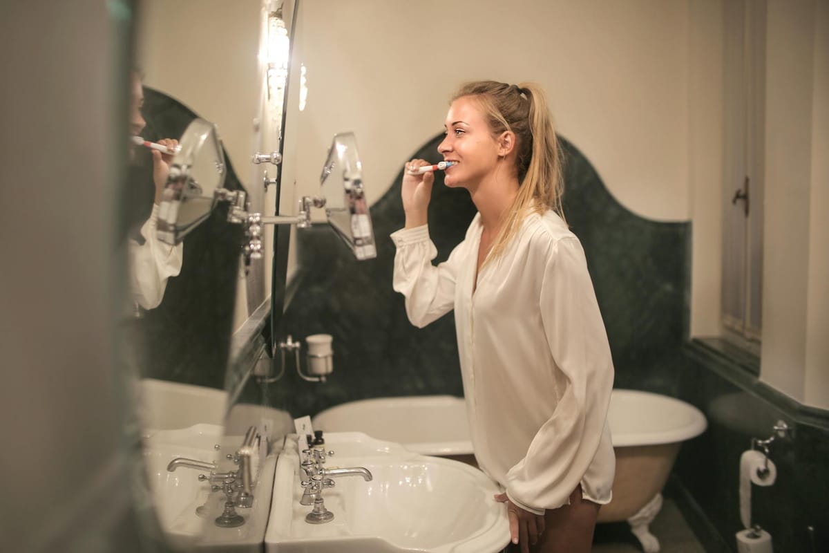 young woman cleaning teeth in bathroom