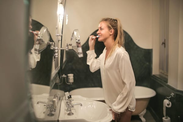 young woman cleaning teeth in bathroom