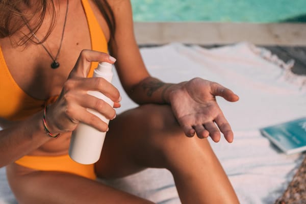 woman in yellow bikini holding white plastic spray bottle
